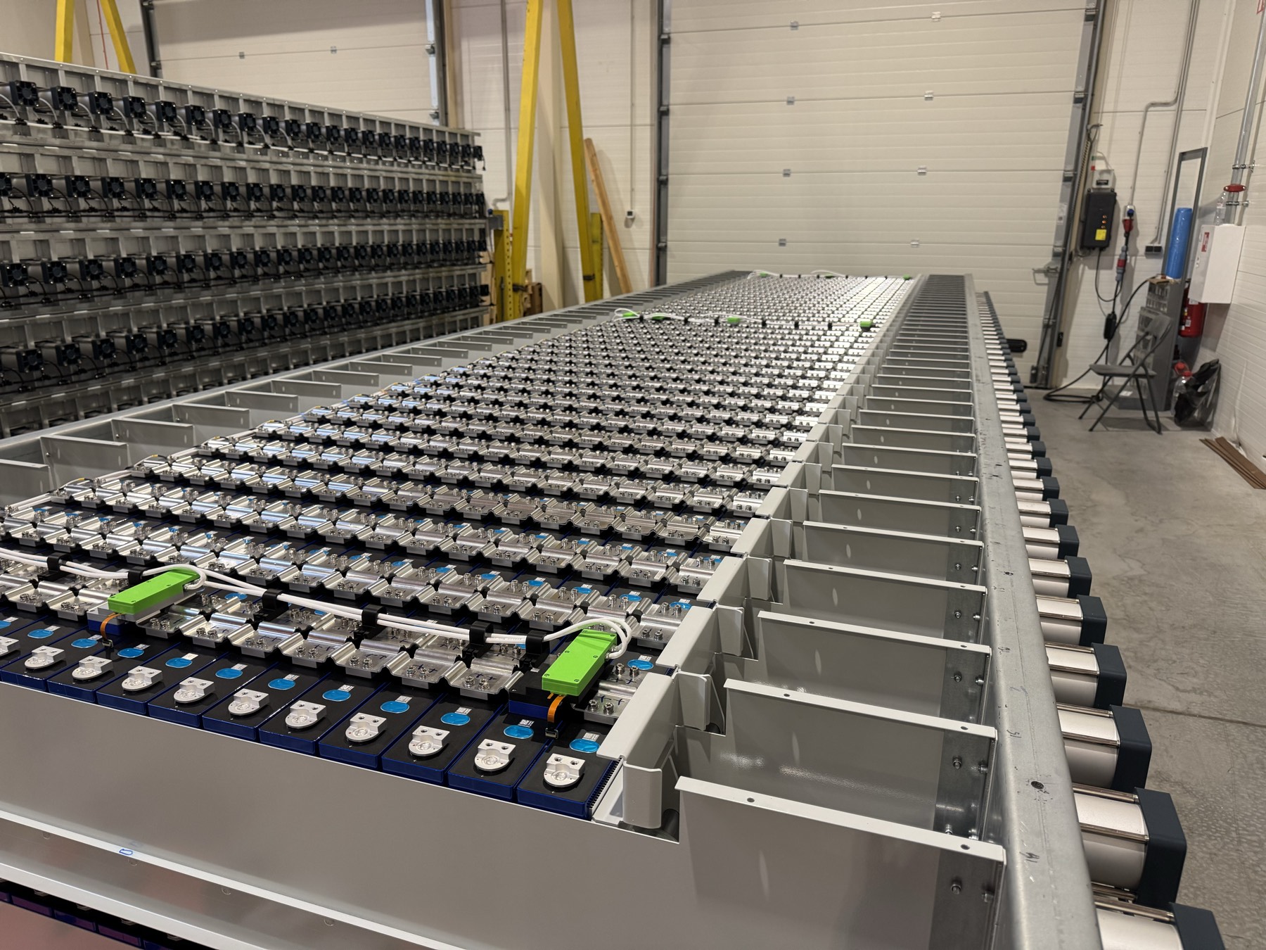 Cells laid into the floor of an Energy compartment during assembly, with module racks alongside.